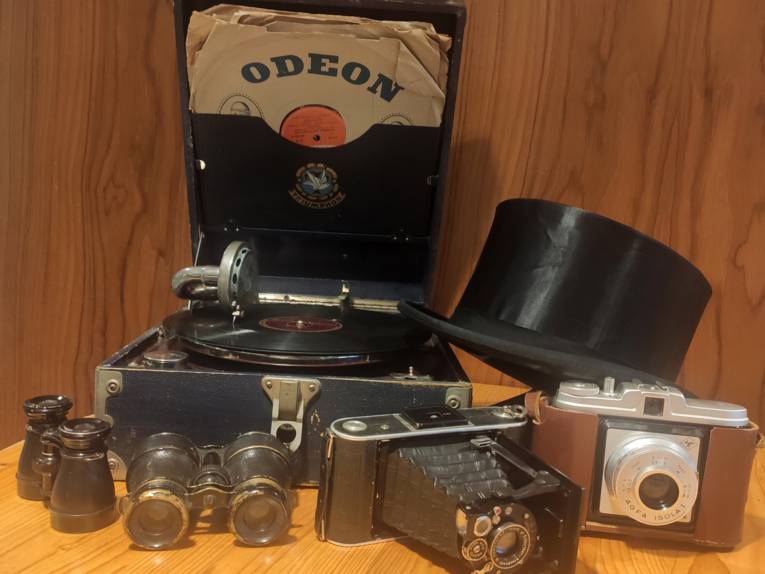 Fotoapparate mit Zubehör, Koffergrammofon mit Schallplatten und Chapeau Claque.