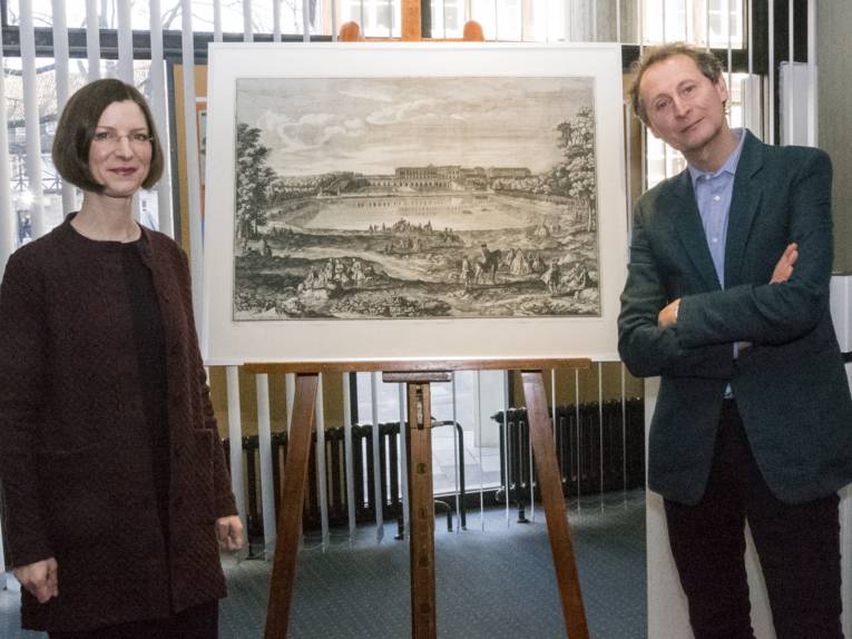 Dr. Annika Wellmann-Stühring und Dr. Andreas Urban neben einer Grafik des Schlosses Versailles