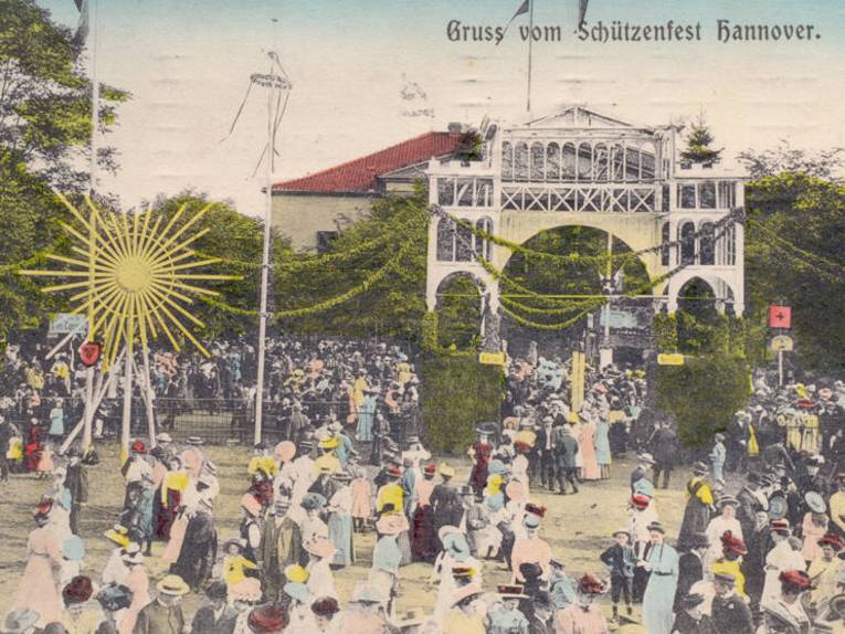 Schützenplatz, Die Postkarte zeigt den Eingang zum Schützenfest neben dem Schützenhaus. Vor und auf dem Festgelände zahlreiche Menschen, Foto-Postkarte, 1910
