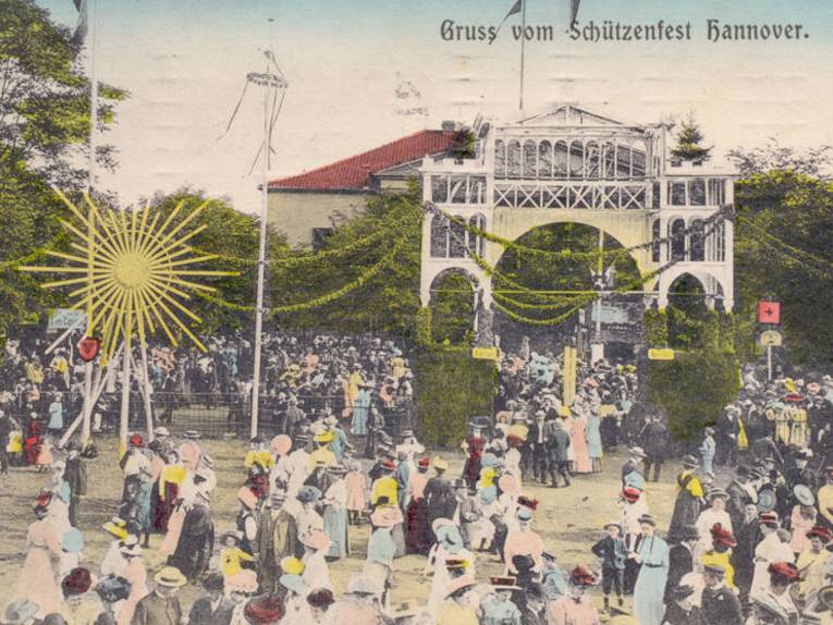 Schützenplatz, Die Postkarte zeigt den Eingang zum Schützenfest neben dem Schützenhaus. Vor und auf dem Festgelände zahlreiche Menschen, Foto-Postkarte, 1910
