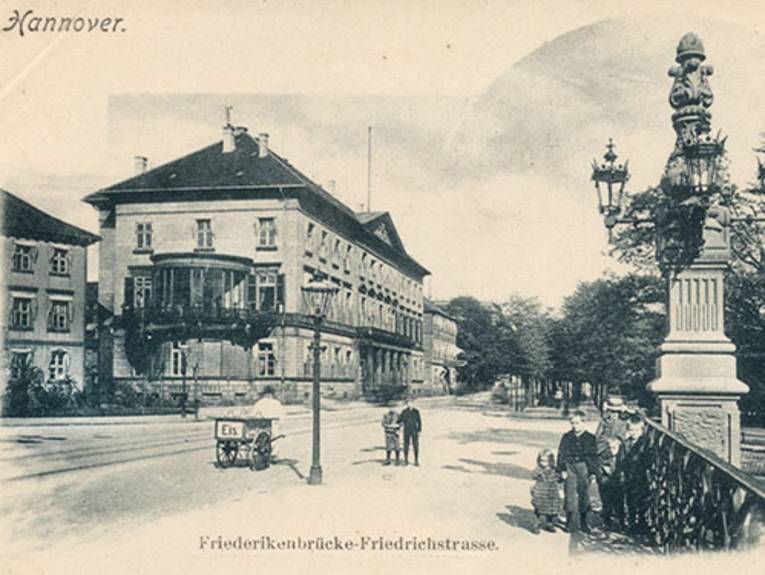 Friedrichswall mit Wangenheimpalais. Postkarte, bezeichnet "Hannover" (oben links) und "Friederikenbrücke-Friedrichstrasse." Das Bild zeigt den Blick von der Brücke über die Friedrichstraße (heute Friedrichswall) auf das damalige Rathaus, das Wangenheimpalais. Im Vordergrund Kinder und ein Karren eines Eisverkäufers. Kandelaber. Foto-Postkarte, 1900-1907