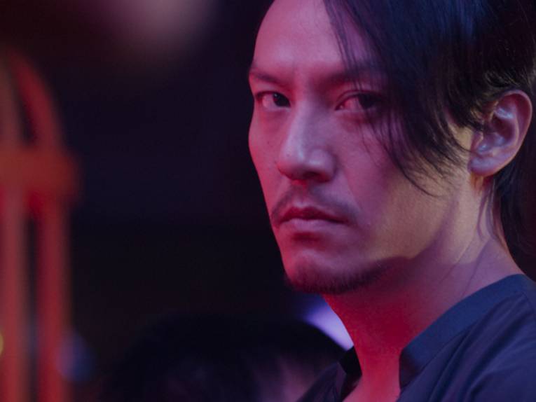 Im Bild zu sehen ist Hauptdarsteller Chang Chen. Er schaut ernst neben die Kamera und ist in magentafarbenes Neonlicht getaucht.