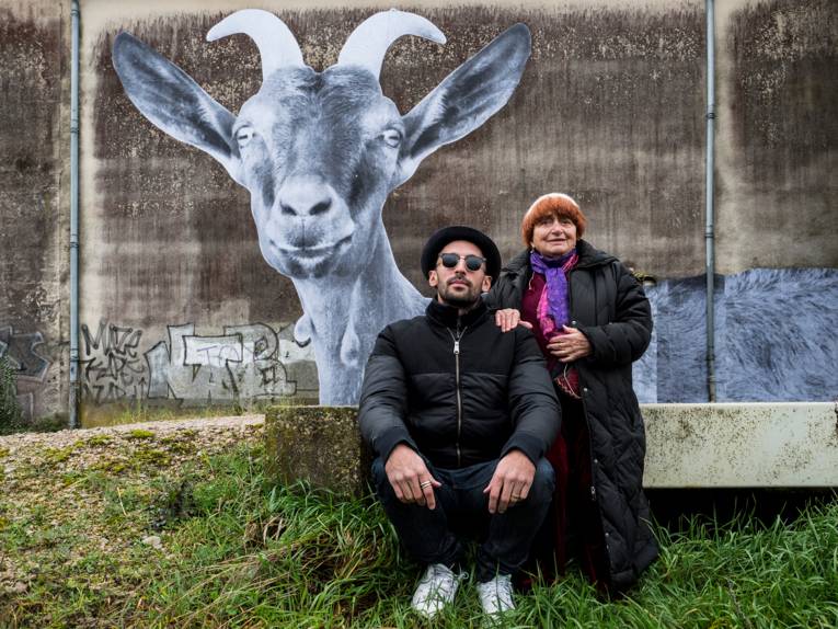 Street-Art-Künstler JR und Regisseurin Agnes Varda. Auf der Mauer im Hintergrund das Foto einer Ziege in schwarz-weiß
