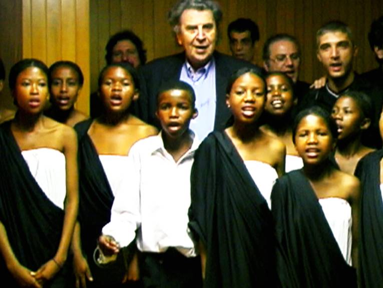 Älterer Mann singt zusammen mit afroamerikanischen Kindern im Chor.