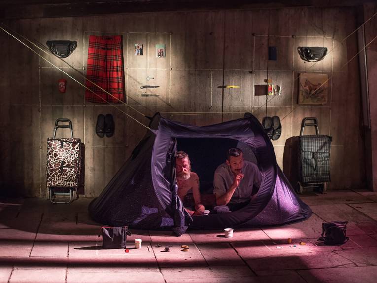 Zwei erwachsene Männer in einem Zelt in der Mitte eines Raumes.