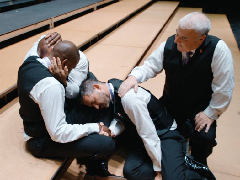 Zu sehen sind mehrere Chormitglieder, die zusammen sitzen und sich gegenseitig mental stärken.