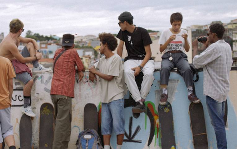 Zu sehen ist eine Gruppe Jugendlicher, die mit ihren Skateboards an einer Mauer abhängen.