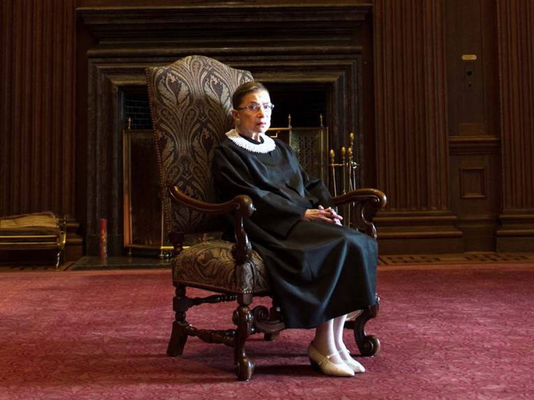 Eine ältere Dame (Ruth Bader Ginsburg, Hauptfigur) sitzt auf einem alten, sesselähnlichen Stuhl.