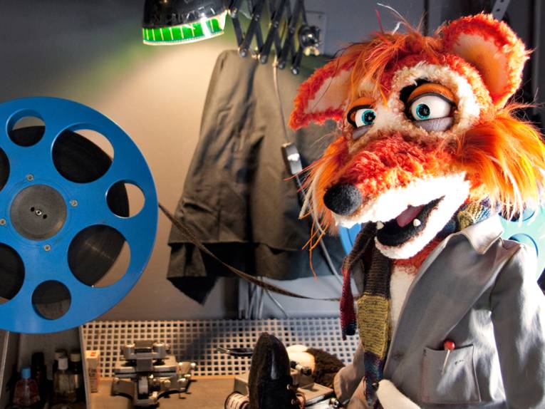 Eine Fuchs-Stoffpuppe mit einer Filmrolle.