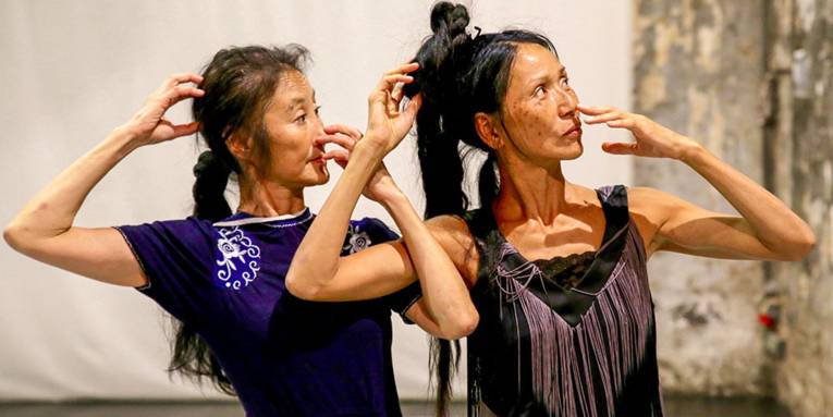 Zwei asiatisch aussehende Tänzerinnen in synchroner Tanzpose