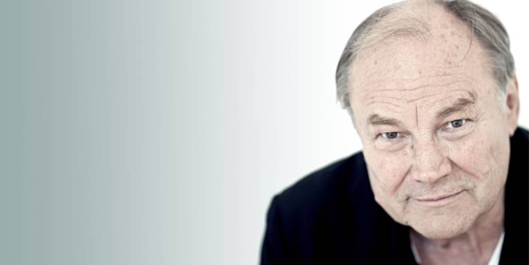 Ein Mann mit hoher Stirn und ausdrucksvollem Gesicht in einem schwarzen Shirt.