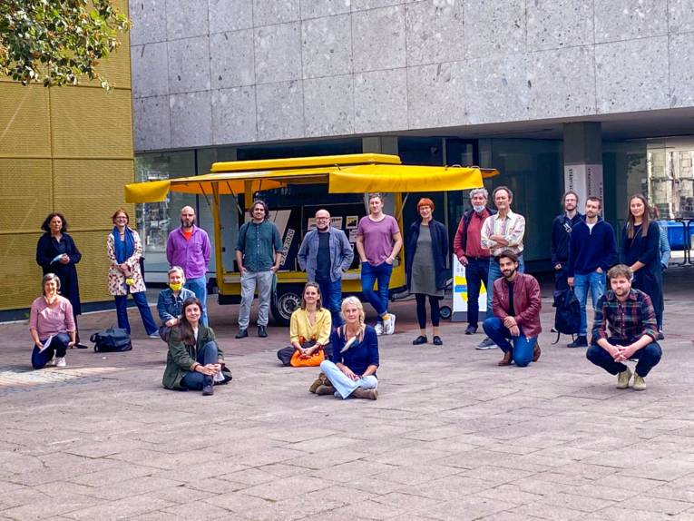 Menschen vor einem gelben Wagen. 