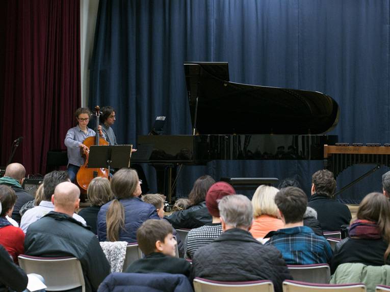 Eine Cellistin und ein Pianist bei einem gemeinsamen Konzert auf der Bühne vor Publikum