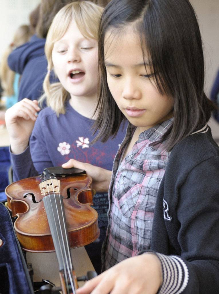 Zwei Mädchen schauen sich eine Violine an.