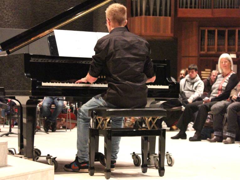 Klavierspieler spielt vor vollbesetztem Publikum