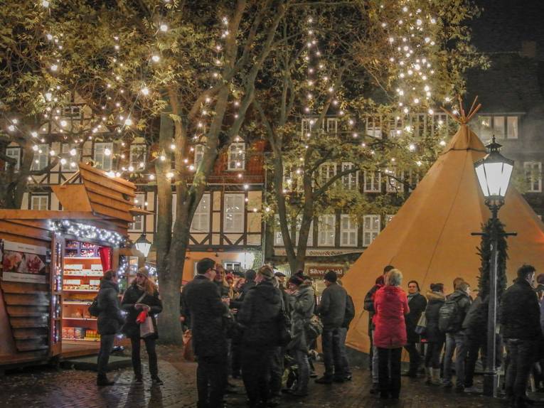 Besucherinnen und Besucher des Weihnachtsmarkt unterhalten sich vor der Kulisse des finnischen Dorfes mit Tipi und Holzhütten