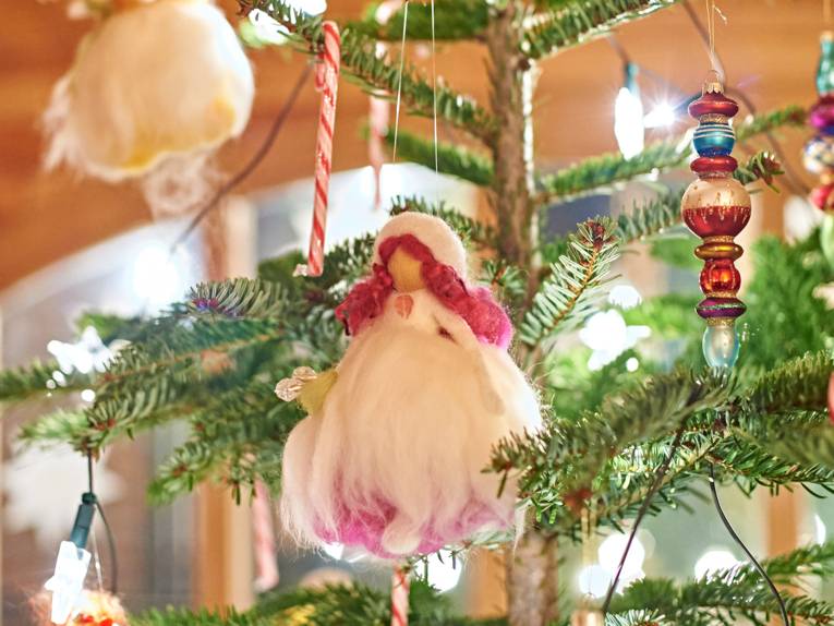 Nahaufnahme einer kleinen handgearbeiteten Puppe, die an einem Weihnachtsbaum zur Dekoration hängt