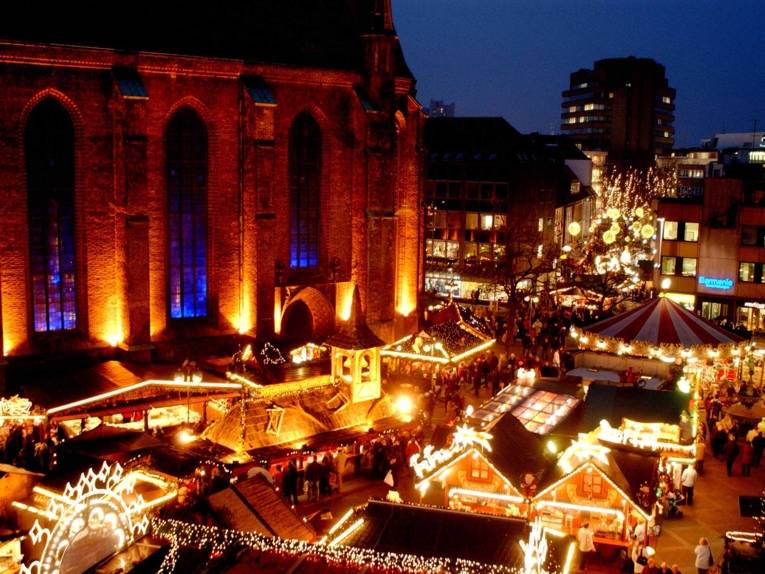 Blick von oben auf das beleuchtete Kirchenschiff der Marktkirche und die aufgebauten Weihnachtsmarktstände