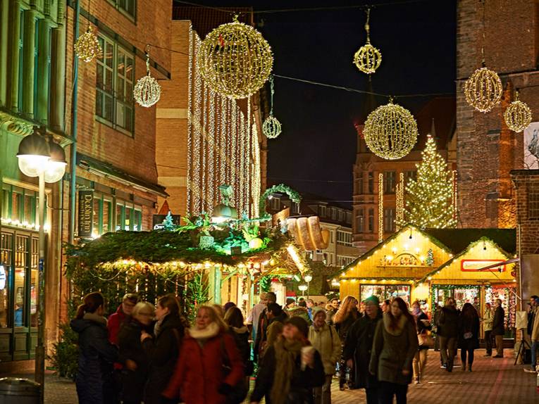 Besucherinnen und Besucher des Weihnachtsmarktes an der Marktkirche schlendern zwischen den mit Tannen verzierten Ständen und genießen die stimmungsvolle Beleuchtung