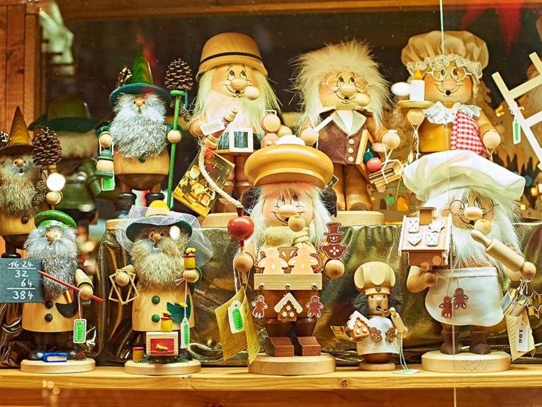 Holzfiguren und Wichtelmännchen, die auf dem Weihnachtsmarkt an einem Verkaufsstand präsentiert werden