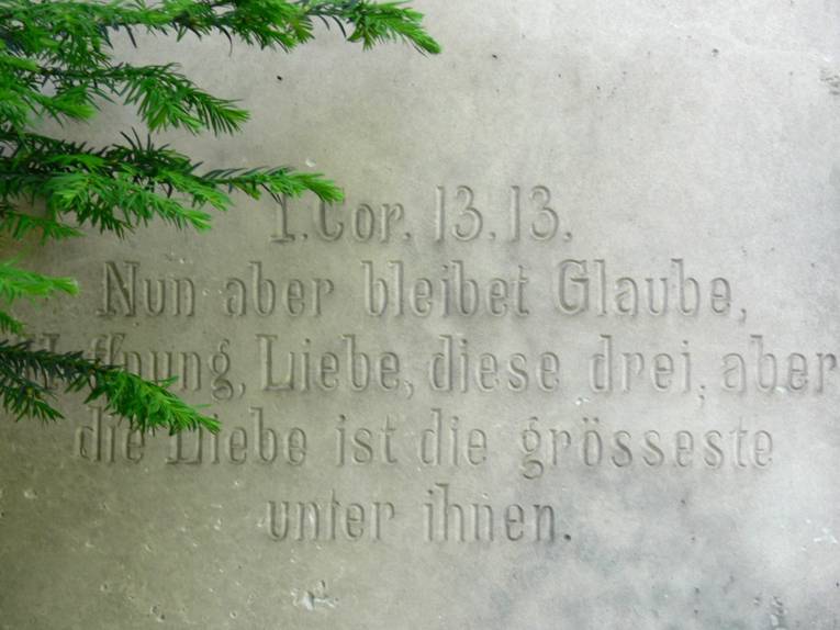 Grabstein mit dem eingravierten Bibelvers "Nun aber bleibet Glaube, Hoffnung, Liebe, diese drei, aber die Liebe ist die größte unter ihnen"