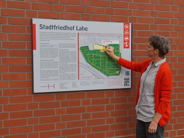 Frau, die etwas an einer Infotafel erklärt. 