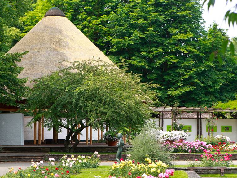 Blick auf das japanische Teehaus im bunt blühenden Stadtpark.