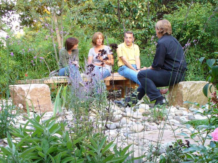 Zwei Frauen und zwei Männer sitzen gemeinsam im Garten