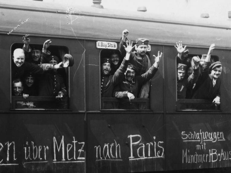 Historische Aufnahme von Soldaten, die aus den Fenstern eines Zuges zum Abschied winken