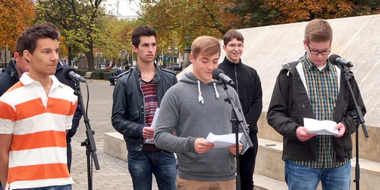 Einige Schüler, die Texte am Holocaust-Mahnmal vortragen