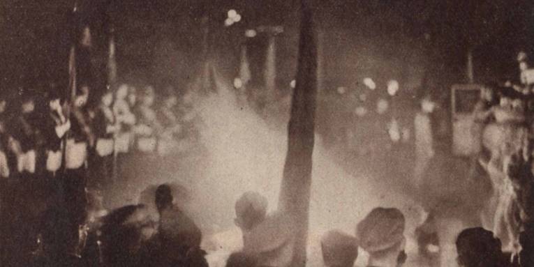 Bücherverbrennung im Mai 1933 in Hannover. Erkennbar haben Vertreter verschiedener studentischer Verbindungen mit ihren Fahnen (links oben) Aufstellung um den brennenden Scheiterhaufen für die Bücher genommen. Abgedruckt in "Die Weltschau" vom 21.05.1933, S. 2.