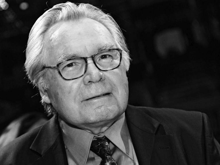 Schwarzweiß-Porträt eines älteren Mannes im Anzug mit Brille.