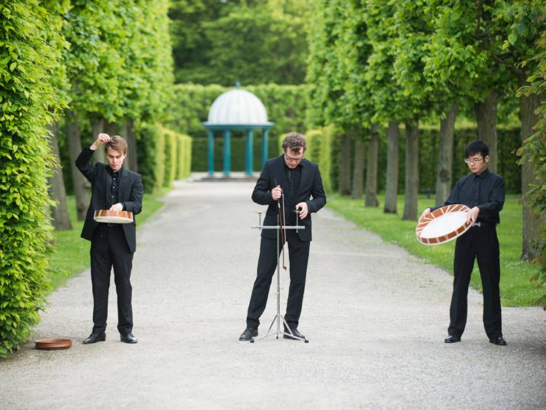 Drei Musiker stehen im Großen Garten und musizieren