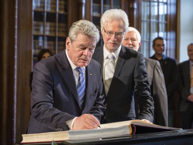 Bundespräsident Gauck trägt sich unter den Augen von Bürgermeister Strauch ins Goldene Buch der Stadt ein