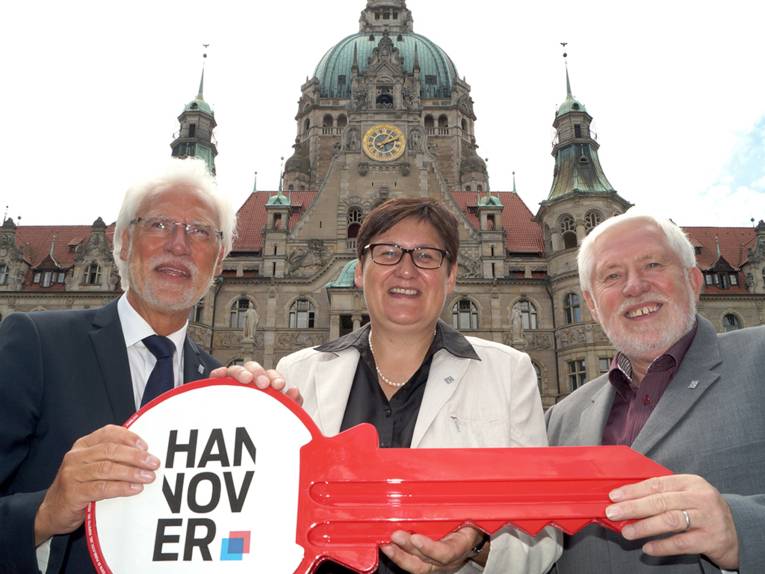Bernd Strauch, Sabine Tegtmeyer-Dette und Hans Mönninghoff vor dem Neuen Rathaus, die drei halten einen großen roten Schlüssel in den Händen