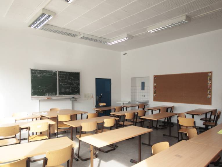 Blick in ein leeres Klassenzimmer an der Leibnizschule, zu sehen sind mehrere Tische und Stühle sowie eine beschriebene Tafel