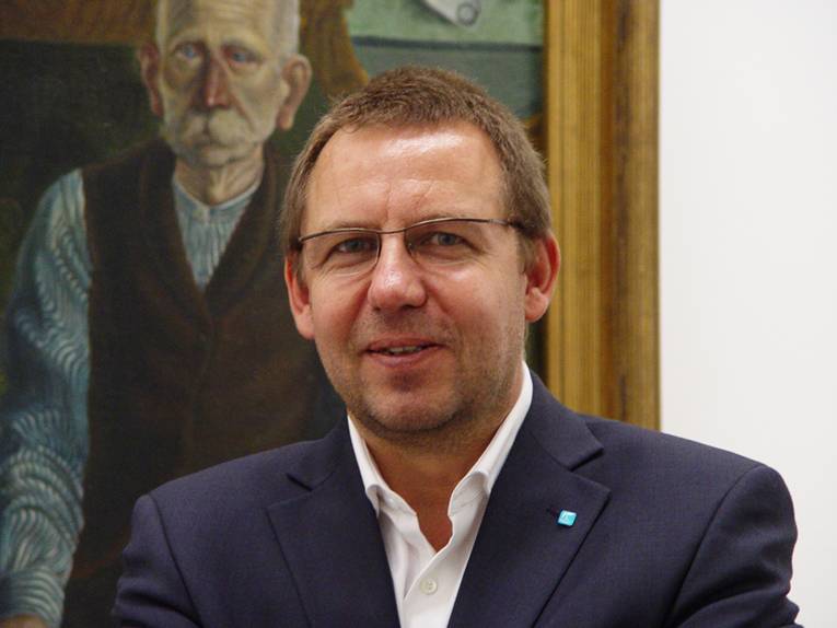 Portraitfoto von Dr. Reinhard Spieler vor einem Gemälde im Sprengel Museum Hannover