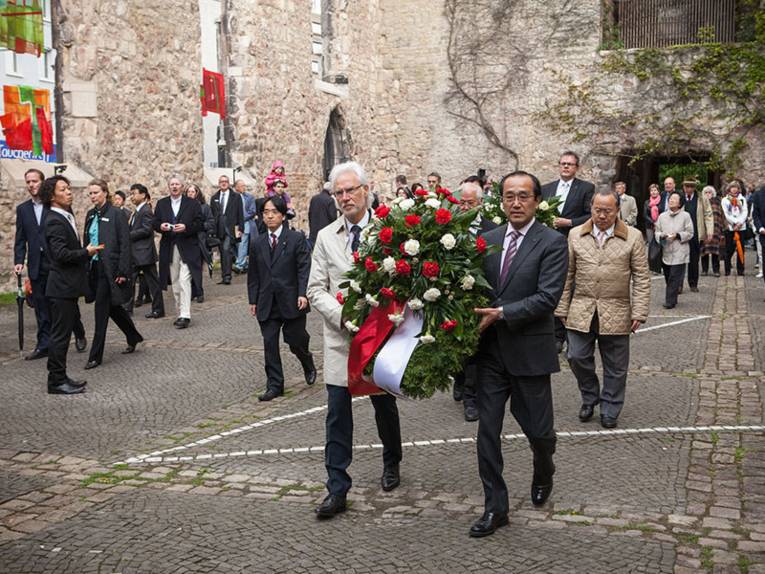 Hannovers Bürgermeister Bernd Strauch und sein Amtskollege Kazumi Matsui aus Hiroshima tragen einen Gedenkkranz in die Ruinen der Aegidienkirche