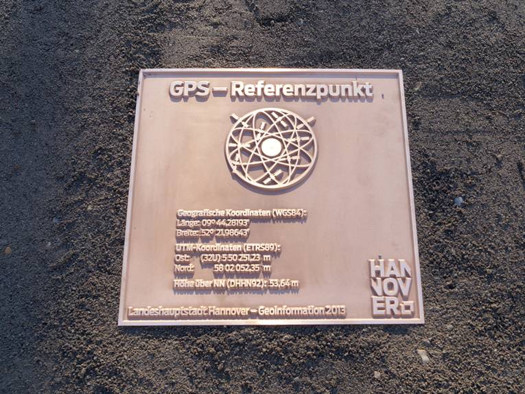 Eine bronze-farbene Bodenplatte mit GPS-Daten