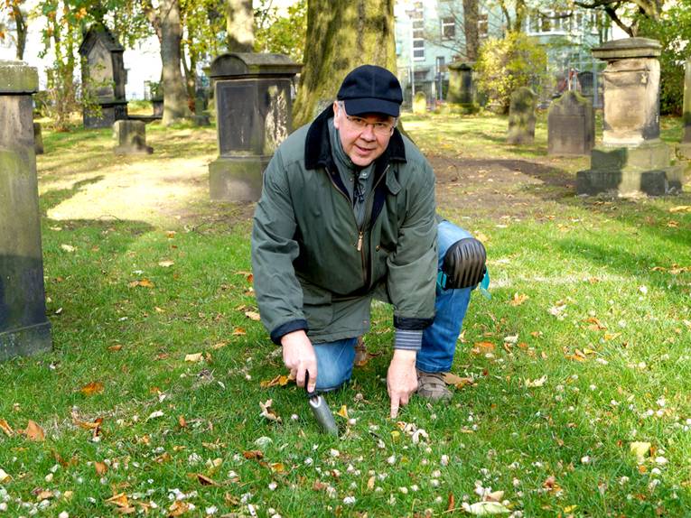 Dieter Zinßer pflanzt eine Blumenzwiebel auf dem Gartenfriedhof