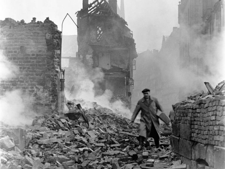 Ein Mann steigt durch die Trümmer eines Hauses