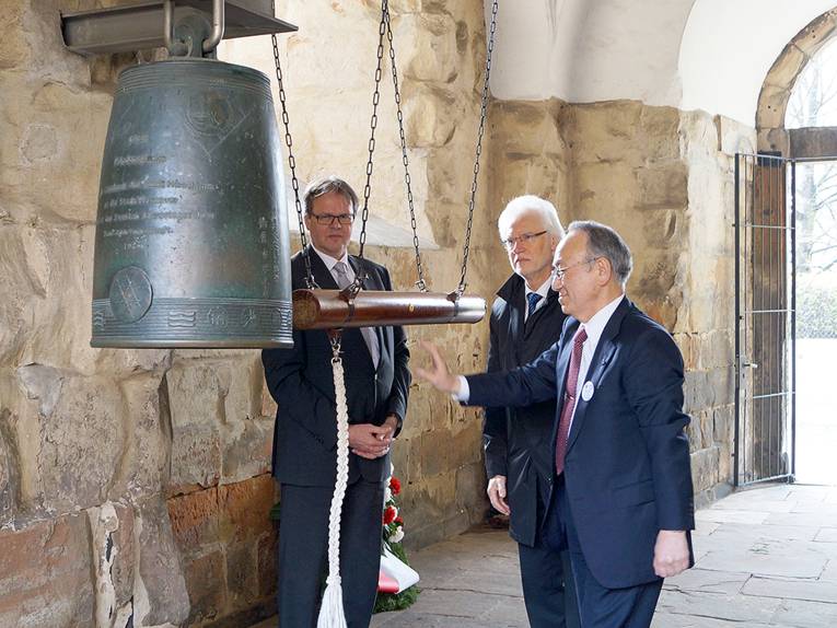 Hans-Martin Heinemann, Bernd Strauch und Dr. Kokui Inai an der Friedensglocke in der Aegidienkirche