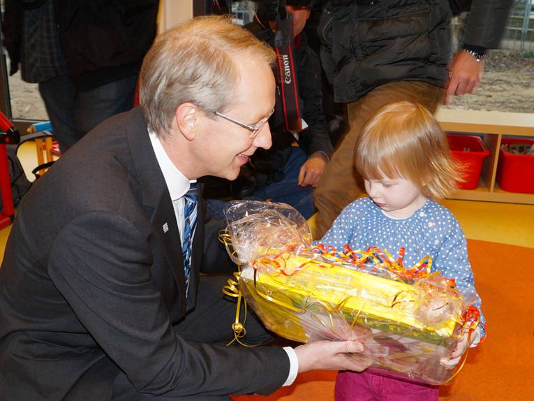 Stefan Schostok überreicht einem kleinen Kind ein Geschenk