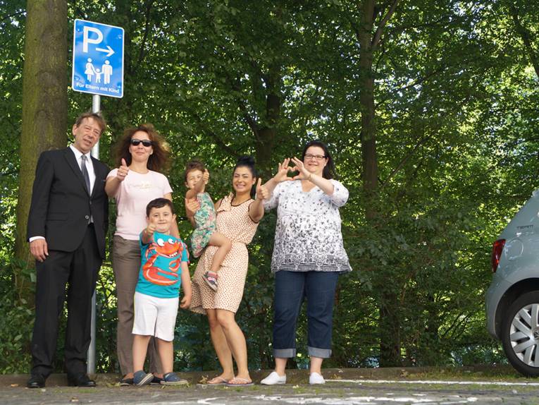 Harald Härke steht mit fünf anderen Personen an einem Schild, das auf Eltern-Kind-Parkplätze hinweist