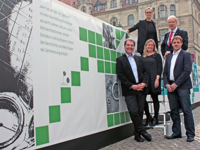 Fünf Personen vor dem plakatierten Bauzaun am Trammplatz