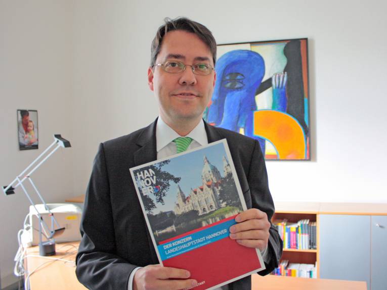 Dr. Marc Hansmann hält die Konzernbilanz der Landeshauptstadt Hannover in der Hand