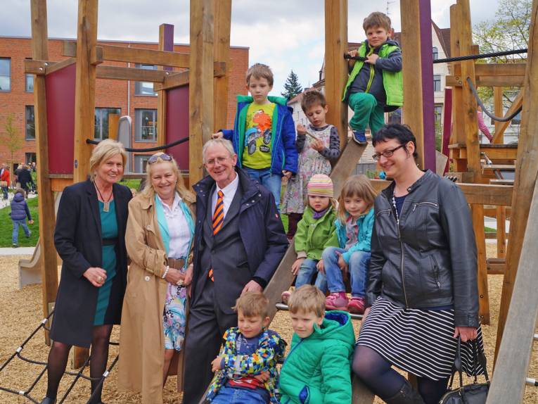 Kita-Leiterin Cornelia Angermann, Bezirksbürgermeisterin Edeltraut-Inge Geschke, Jugend- und Sozialdezernent Walter, Ratsfrau Petra de Buhr inmitten von Kita-Kindern, die auf einem Spielgerüst klettern