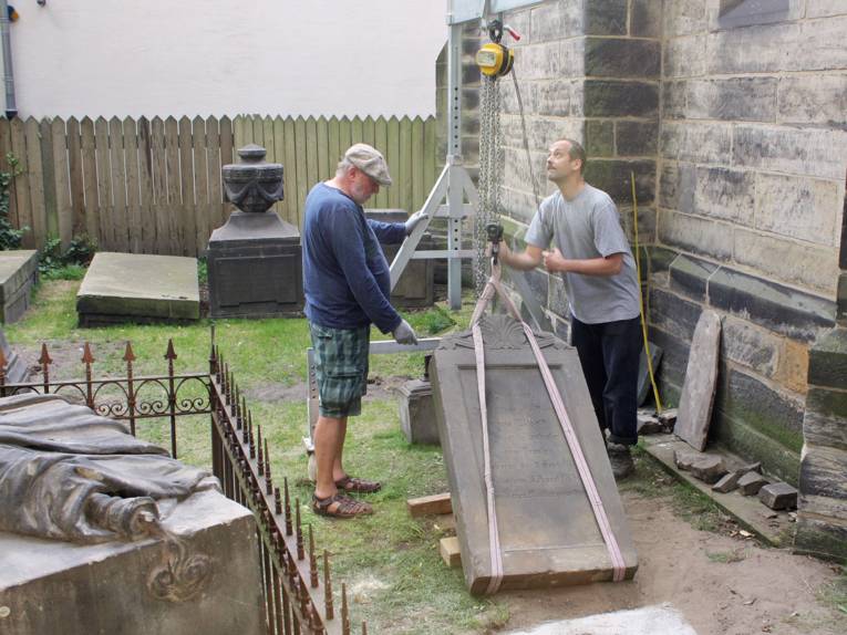 Zwei Arbeiter stellen das Grabmal von Charlotte Domeier auf