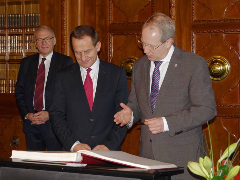 Alfons Hörmann und Stefan Schostok werfen einen Blick in das Goldene Buch, im Hintergrund Dr. Michael Vesper