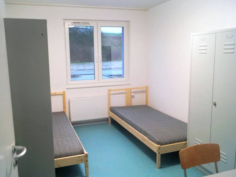 Blick in ein Zimmer im Flüchtlingswohnheim Hermann-Ehlers-Allee: Zwei Betten, zwei Spinde, ein Tisch und zwei Stühle